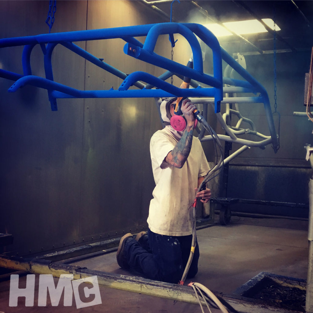 Powder coating technician powder coating a blue UTV cage